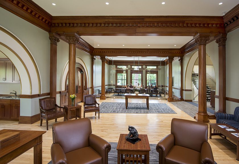 chairs and couches provide a variety of seating areas surrounded by plaster walls and ornate woodwork