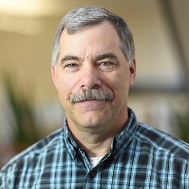 portrait of a man in a green and blue plaid shirt