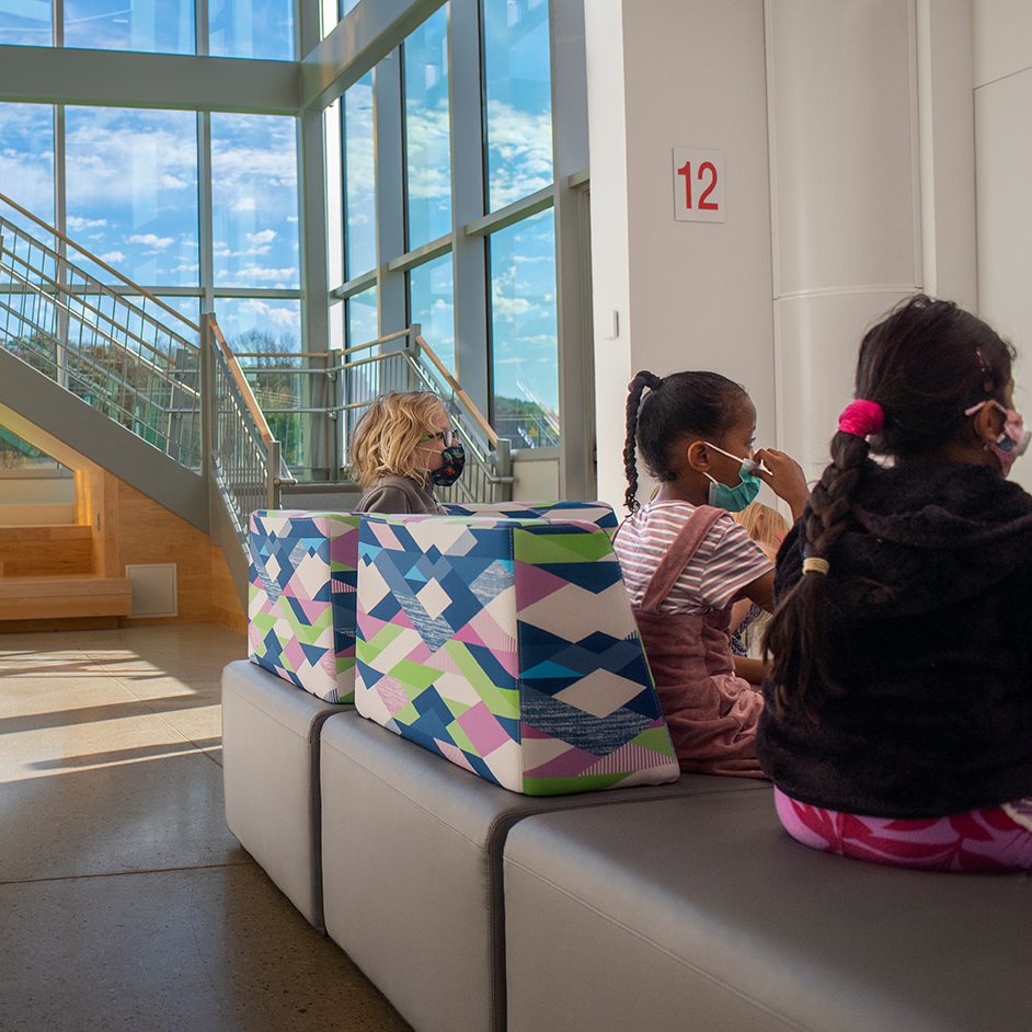 children in masks sit near an air diffuser