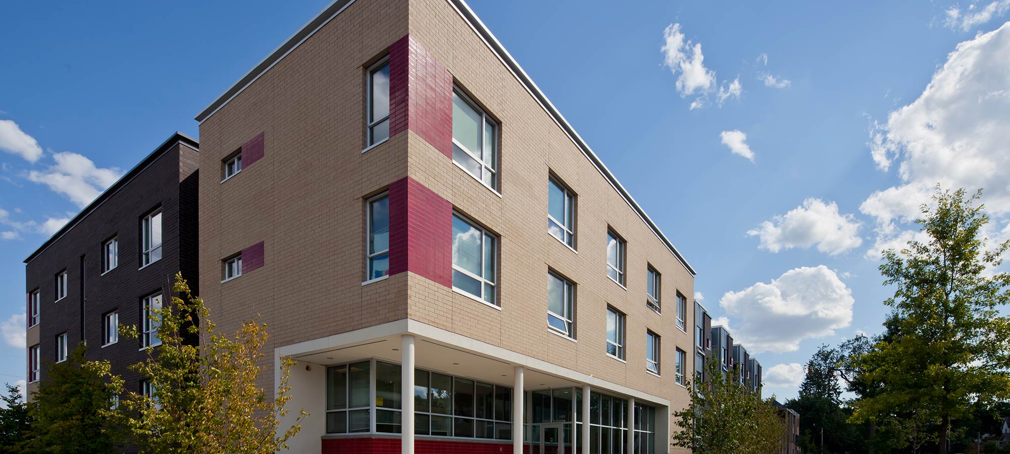 corner view of a 3 story building with brick and tile exterior